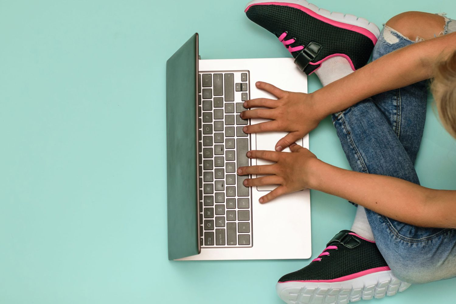 Kind mit Laptop auf Boden sitzend